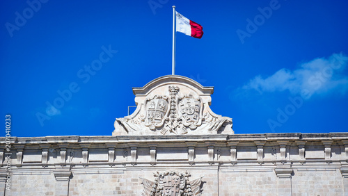 Foto Maltese National Flag Waving over Historic Government Building Facade