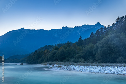 Discover the serene beauty of the Soca River as twilight settles over Bovec, creating a peaceful atmosphere surrounded by nature.