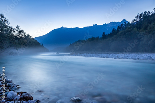 Discover the serene beauty of the Soca River as twilight settles over Bovec, creating a peaceful atmosphere surrounded by nature.