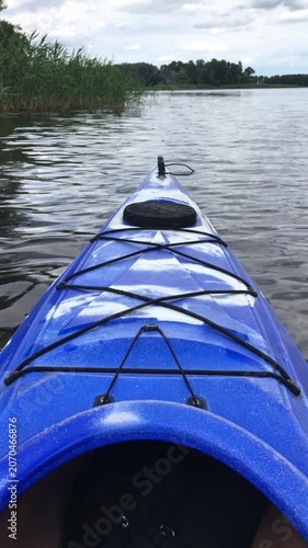 POV shot of a blue kayak floating on calm lake water.