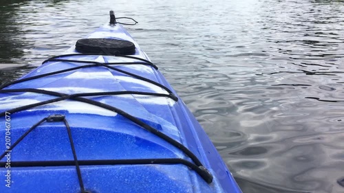 POV shot of a blue kayak floating on calm lake water.