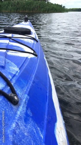 POV shot of a blue kayak floating on calm lake water.