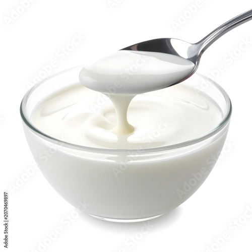 Thick creamy yogurt dropping from a silver spoon into a glass bowl with culinary