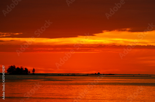 Vibrant Borneo sunset over calm waters featuring intense orange and red hues across the evening sky.