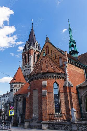 Historic St. Stanislaus Church in Chortkiv, Ternopil region, featuring Gothic Revival architecture, brick walls, towers, and spires under a blue sky.