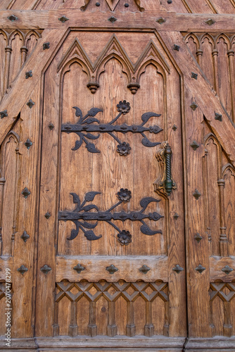 The historic entrance of St. Stanislaus Church features ornate wooden doors with detailed carvings, decorative ironwork, and Gothic Revival stone architecture.