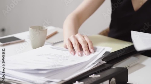 Professional hands sorting through business documents and reports in modern office workspace for organizational tasks
