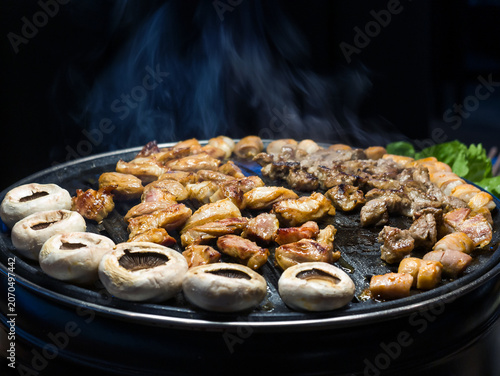 Sizzling Grilled Meat and Mushrooms on a Barbecue Plate with Smoke