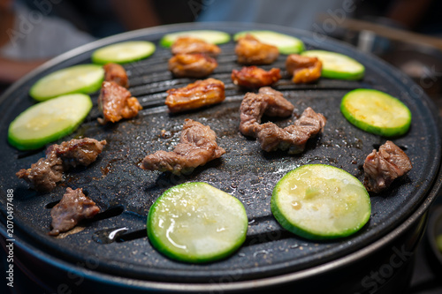 Grilled Meat and Sliced Cucumbers on a Hot Plate in a Restaurant Setting