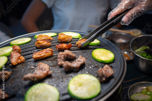 Grilling Meat and Vegetables on a Hot Plate with Tongs in a Restaurant Setting