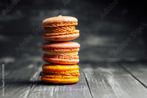 Obraz na plátne Stack of colorful macarons on dark wooden surface