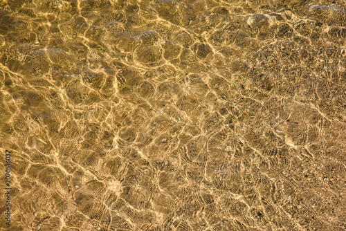 Sunlight interacting with ripples on water surface creating interesting patterns on lake Michigan beach.