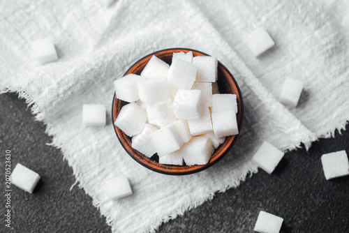 Cube sugar in a wooden bowl on a textured cloth, ideal for sweetening drinks