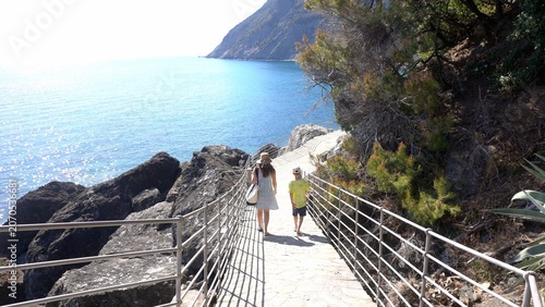 Italy , Liguria , Genoa La Spezia - mother and son walking by the sea -  the seaside path way  via del mare, seafront walk  in Framura close to Cinque Terre - tourist attraction destination for summer