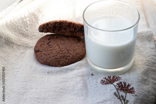 Bilde på lerret Chocolate chip cookies and a glass of milk on a linen tea-towel