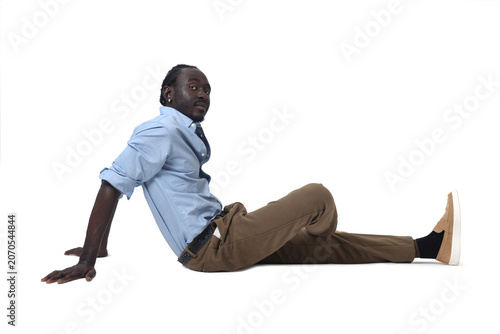 side view of a man sitting on he floor legs crossed looking at camera on white background