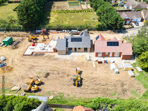 Interesting drone UAV view of a new detached bungalows being built within a small building plot in Cambridgeshire, UK. Established homes surround the site.