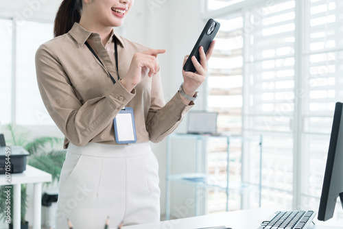 Young Businesswoman Working at Office Desk While Managing Documents and Mobile Communication.