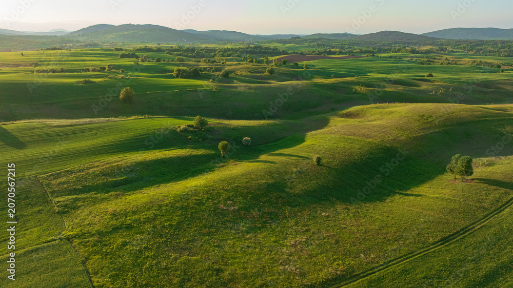 Naklejka premium Drone shot displays rural landscape of Dreznik area near Plitvice Lakes. Green agricultural fields, farm lands, and countryside roads spread across traditional Croatian village territory.