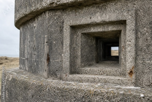 Close-up of a grey concrete blockhouse, square firing port and rough textured surface.