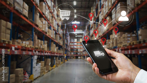 Person Holding Smartphone for Digital Logistics Management and Order Tracking in a Large Industrial Warehouse Facility