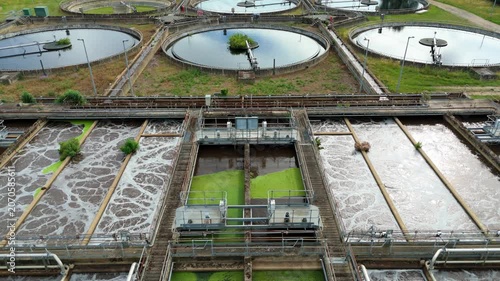 Close-up aerial view of a huge sewage wastewater treatment plant with circular clarifiers and active aeration ponds in Hoddesdon, UK.