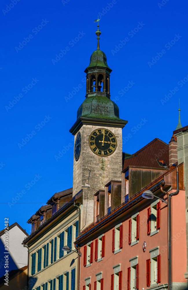 Obraz premium Der historische Uhrturm des Rathauses über den bunten Häuserzeilen der Altstadt in Bulle, Schweiz