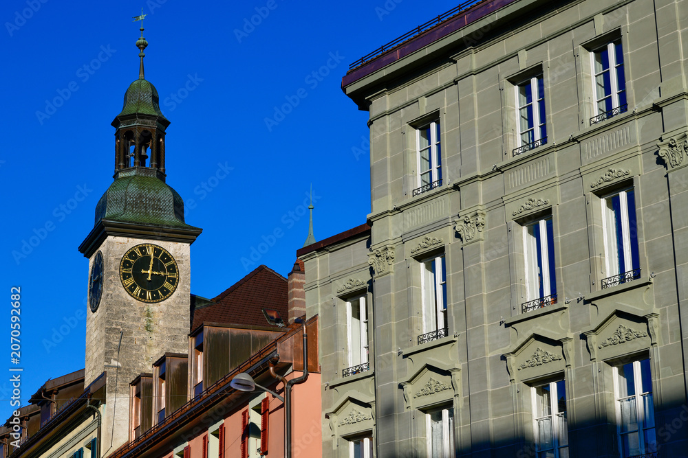Fototapeta premium Der historische Uhrturm des Rathauses über den bunten Häuserzeilen der Altstadt in Bulle, Schweiz