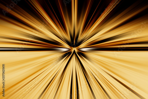 Abstract radial zoom blur in gold, brown and cream tones on a black background, creating a warm radiant flash with textured light beams spreading outward in a dynamic visual burst.