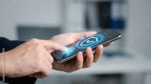 Hands holding a smartphone a blue shield icon on the screen security protection