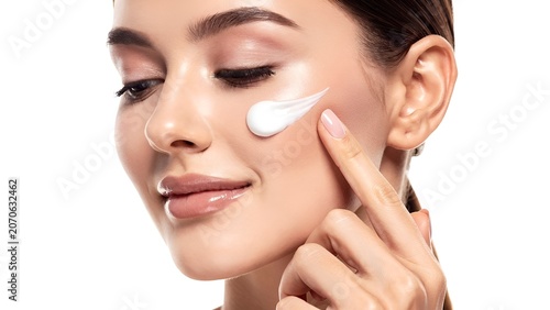 Elegant woman applying luxury skincare cream on face with soft studio lighting on clean white background