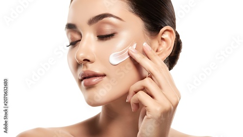 Elegant woman applying luxury skincare cream on face with soft studio lighting on clean white background