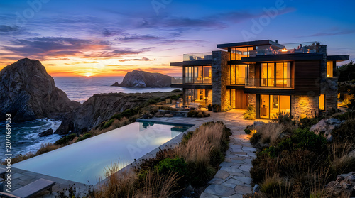 Luxury modern mansion on cliffside by ocean at sunset.