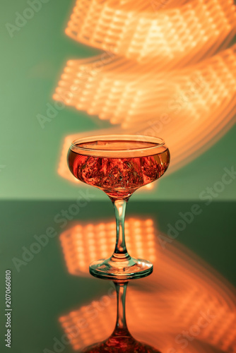 A glass of champagne on the bar, illuminated by bright neon lights in the background.