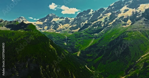 Establishing shot of Switzerland. Aerial view of the green meadows of Switzerland, with the Alps and clouds in the background
