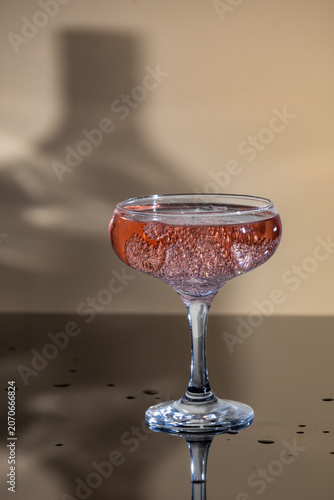 alcoholic cocktail with sparkling wine and ice in champagne glasses, background with bottle shadow in the background