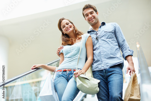 Tableau sur toile Retail, couple and smile with bags on escalator for clearance sale, weekend outing or support