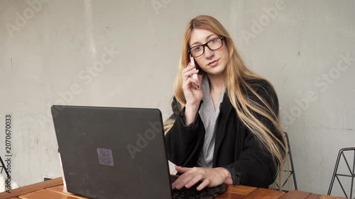 Young businesswoman multitasking with laptop and phone call