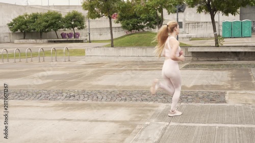 Athletic blonde woman jogging in urban park for fitness