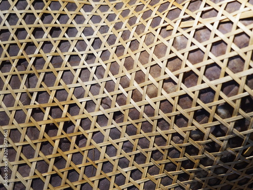 Фотография Traditional Asian bamboo woven hat known as Ngob hanging on a wooden wall next to a close-up texture of its hexagonal weave pattern