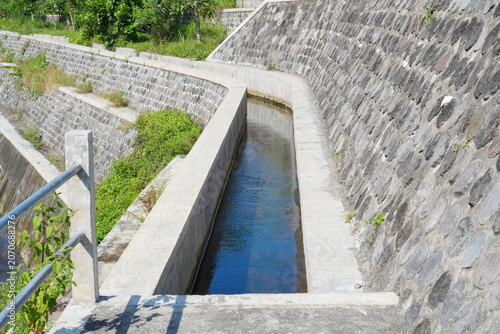 Concrete irrigation canal with stone retaining walls.