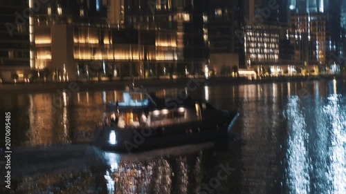 Exclusive Vessel Gently Navigates Tranquil Marina Waters Under Glowing Lights And Calm Evening Sky