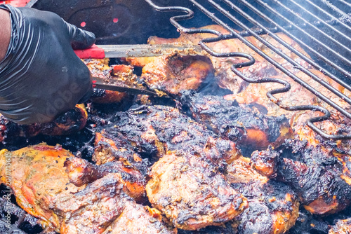 Gloved Hand with Tongs Cooking Chicken on an Outdoor Grill in New Orleans, LA, USA
