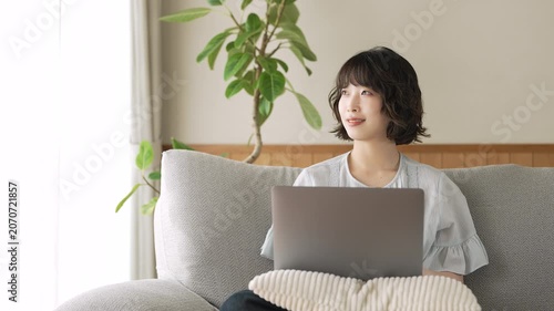 リビングのソファでノートパソコンを使う女性, Woman Using a Laptop on a Sofa in the Living Room