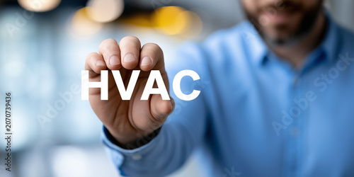 Man holding glowing white HVAC text concept with a blurred office background.