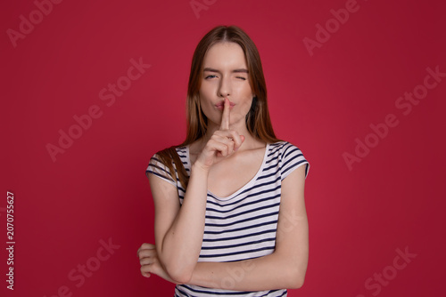 фотографія Playful woman making silence gesture on red background