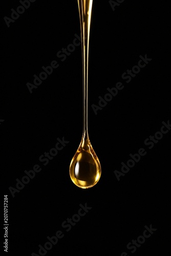 A droplet of golden liquid falling in slow motion against a dark background.