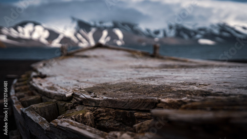 Decayed Wooden Whaling Boat Hull on Antarctic Black Beach with Snow Mountains