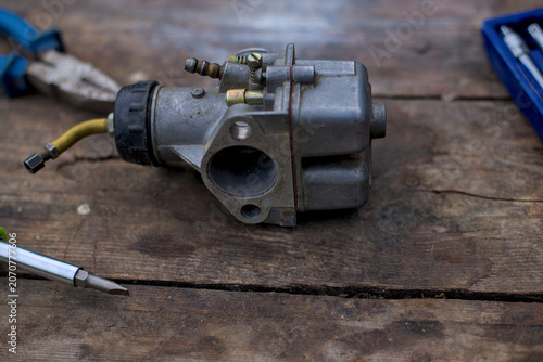 Photo of used carburator on wooden table