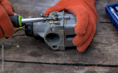 Mechanic disassembles the carburetor with a screwdriver
